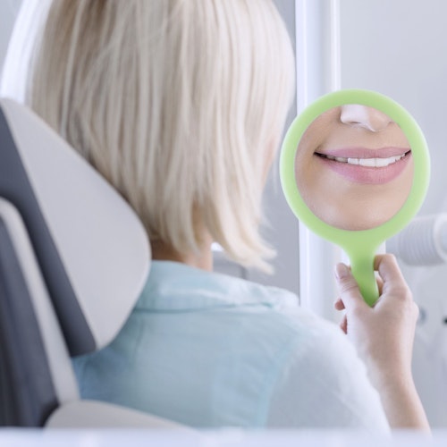 A woman looking at her smile in the mirror