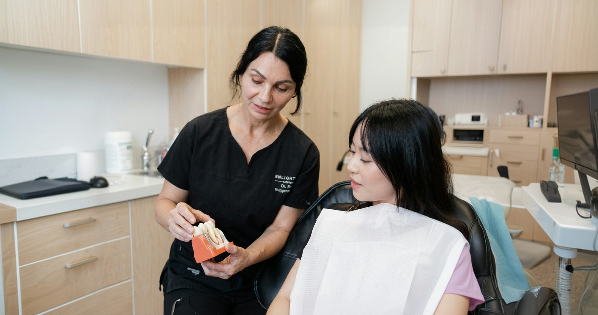 Enlighten Dental team member showing patient a model